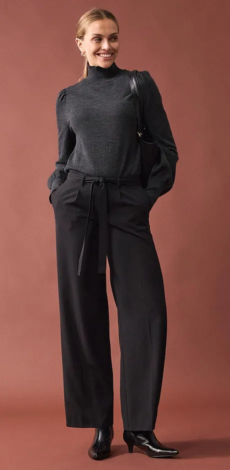 Pull à col roulé gris associé à un pantalon large.