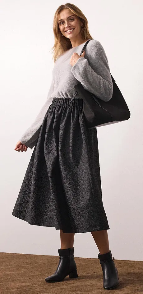 Pull gris et jupe longue noire.