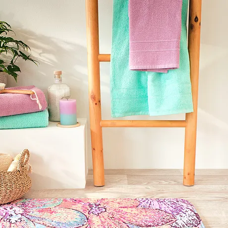 Serviettes de toilette moelleuses aux couleurs pastel, étendues sur une échelle en bois. Tapis multicolore au sol.