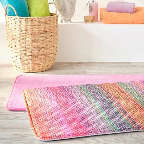 Des serviettes de toilette colorées et un tapis de bain coloré apportent de la fraîcheur dans la salle de bain.