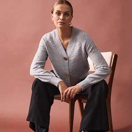 Gilet en maille gris élégant à gros boutons, associé à un pantalon noir.