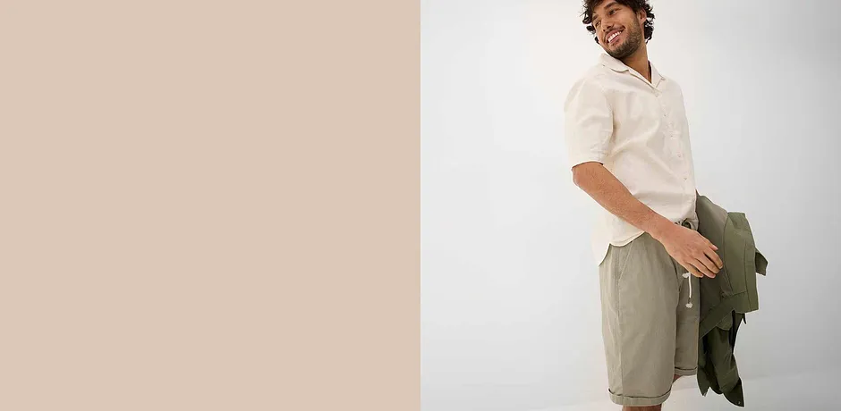 Chemise blanche légère avec col, short beige et veste verte pour un look estival décontracté.