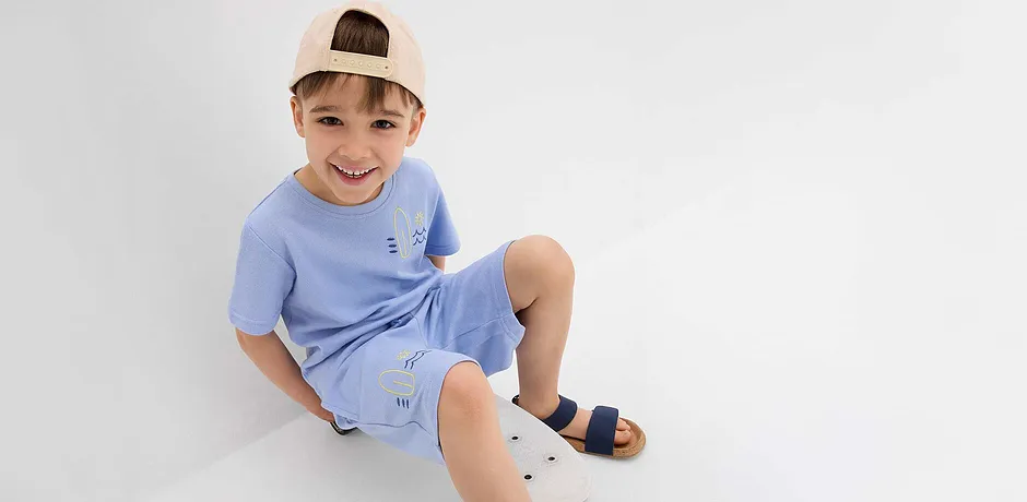 T-shirt bleu clair et short à jolies broderies, casquette baseball beige et sandales bleu foncé.
