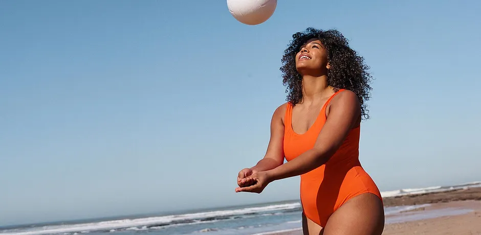 Maillot 1 pièce orange éclatant pour la plage. Le chic sportif sous un ciel bleu azur.