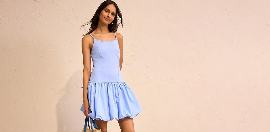 Robe bleu clair estivale à fines bretelles avec jupe évasée, complétée d'un sac en paille.