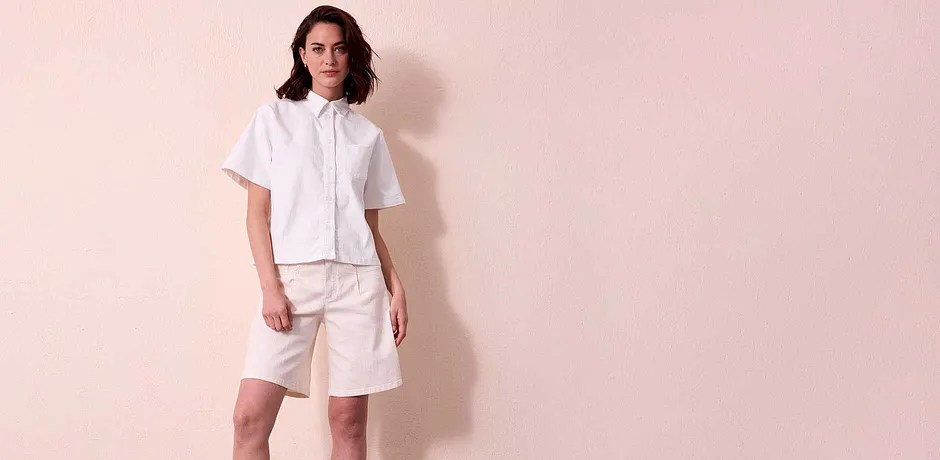 Tenue d’été en blanc : chemisier en jean à manches courtes et col et bermuda.