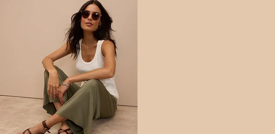 Débardeur blanc, pantalon vert olive et sandales marron - un look d'été décontracté rehaussé d'une paire de lunettes de soleil.