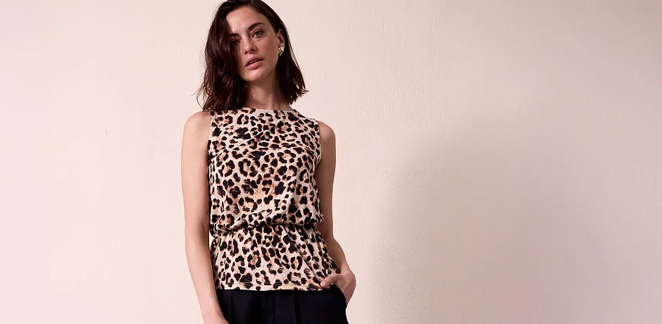 Blouse sans manches à imprimé léopard, élégante et stylée, associée à un pantalon noir qui contraste avec l’imprimé sauvage.