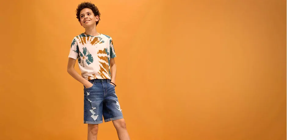 Tenue d’été avec une chemise colorée et un short en jean effet destroyed.