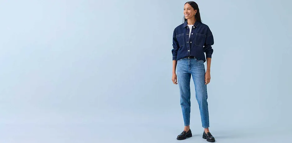 Tenue décontractée avec veste en jean, top blanc et jean bleu clair. Une paire de chaussures noires complète la tenue.