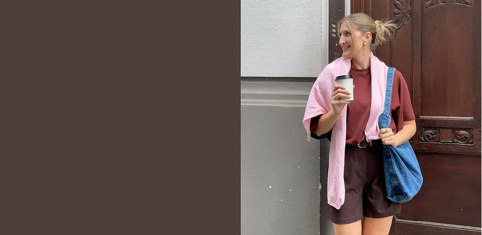 Tenue estivale avec pull rose, short marron et sac bleu.