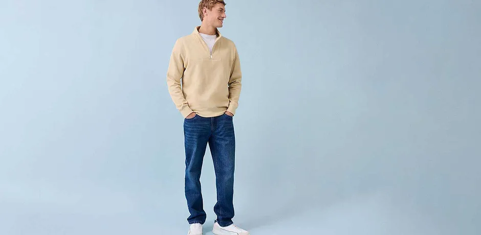 Look décontracté avec pull couleur crème, jean bleu et baskets blanches.