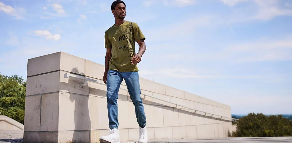 Look décontracté avec un T-shirt vert olive et un jean bleu clair.