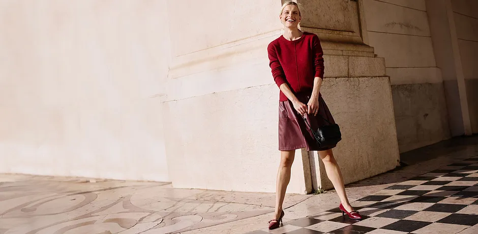 Pull rouge et jupe courte rouge, un sac noir complète la tenue.