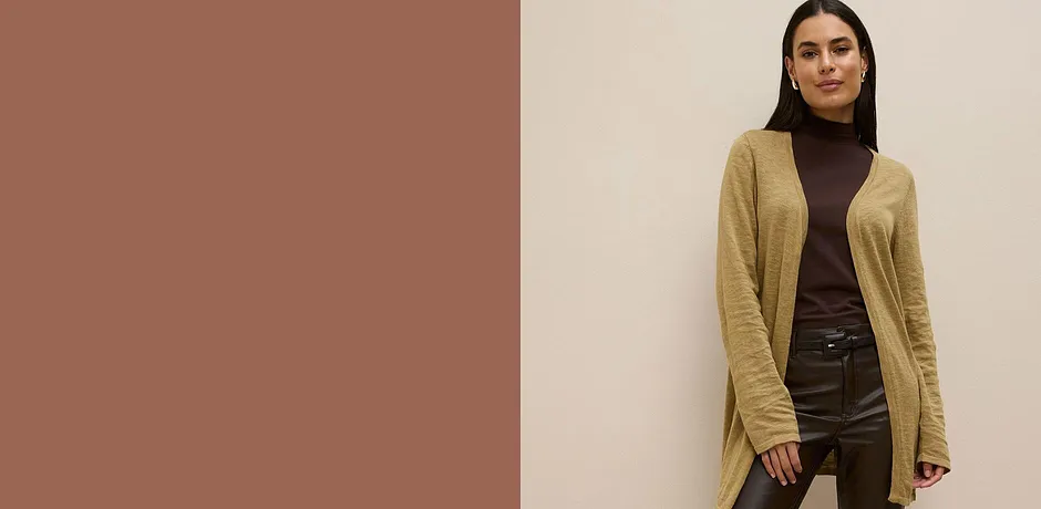 Gilet en maille kaki sur un pull à col roulé marron, associé à un pantalon foncé.